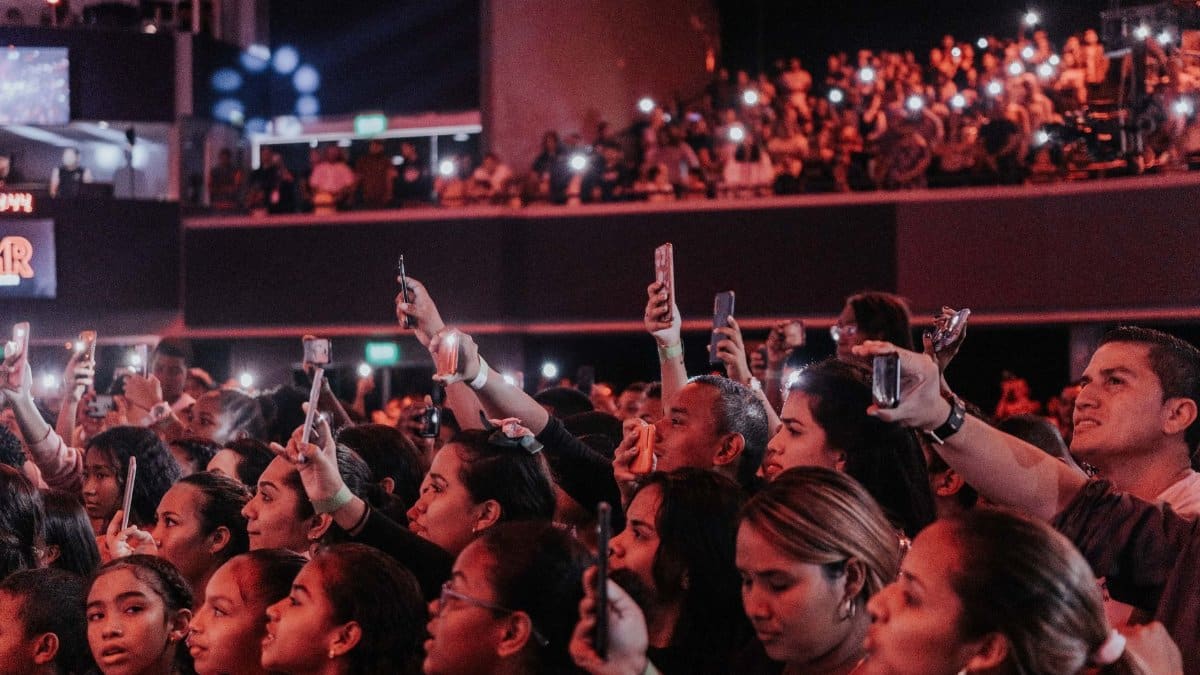 Lively audience enjoying a concert, capturing moments with smartphones in a vibrant atmosphere.