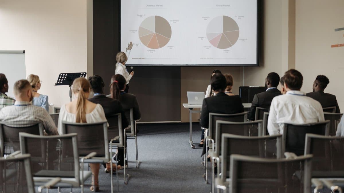 Business conference with diverse audience and speaker presenting market data.
