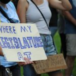 A group of people in Baltimore, Maryland, protesting with handmade signs advocating for legislative change.