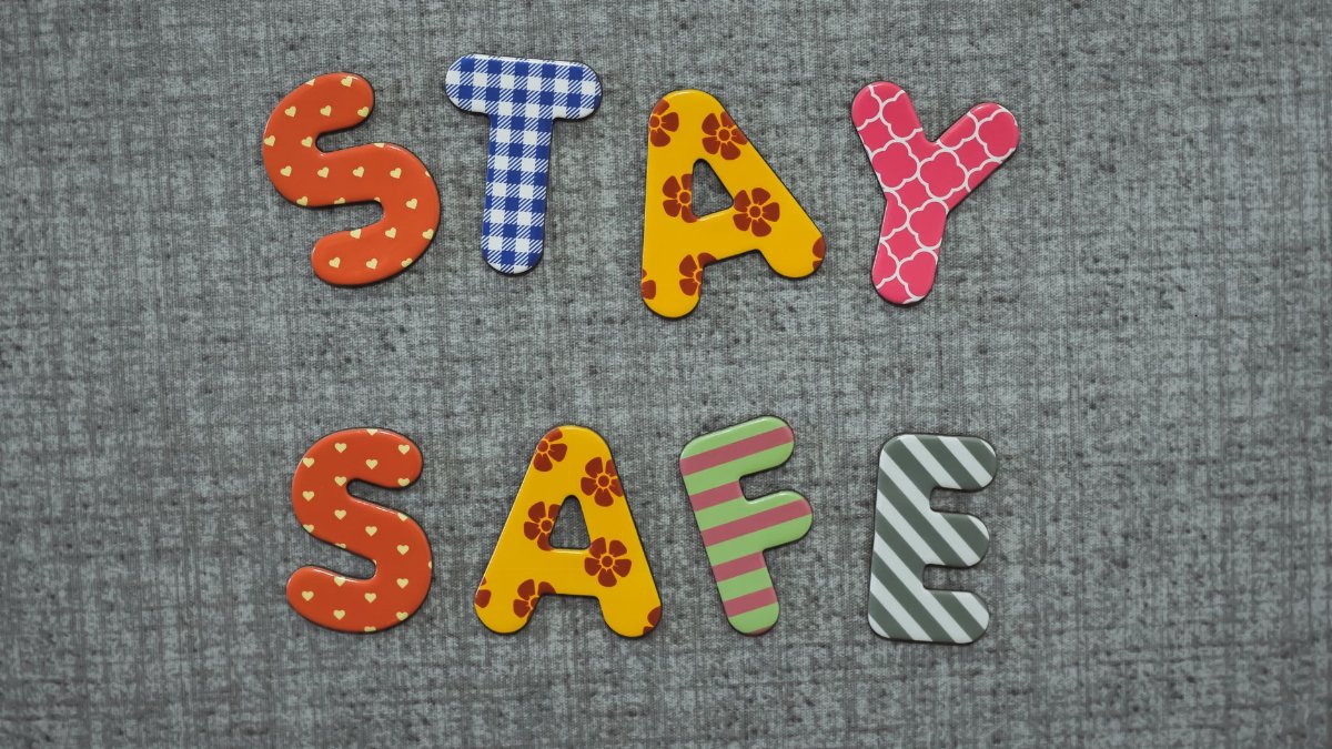 Colorful 'Stay Safe' message in playful, patterned letters on a textured background.