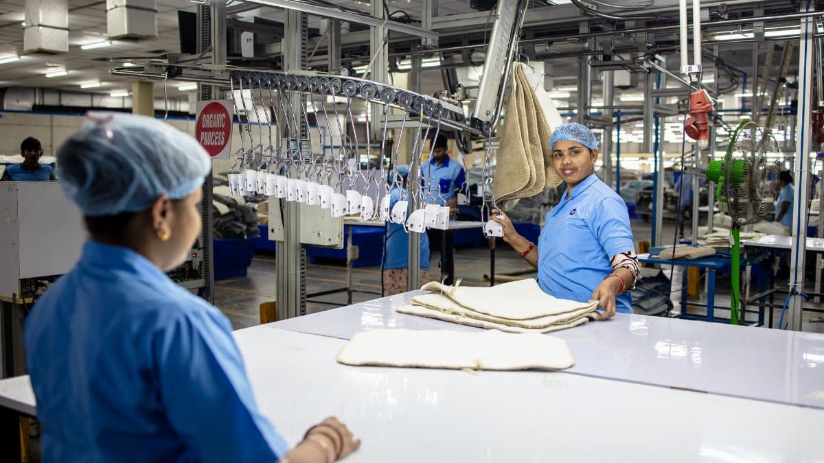 Workers organize fabrics in a textile factory using an automated system.