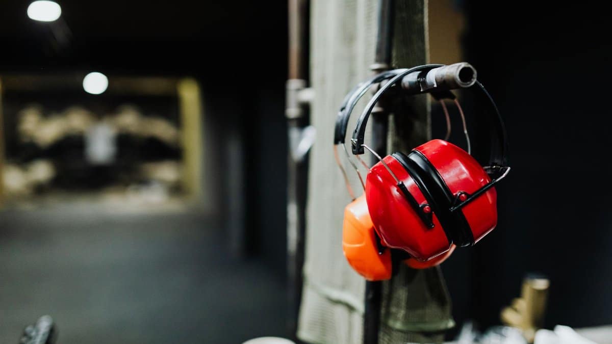 Red ear muffs hanging at an indoor shooting range, offering essential safety gear.