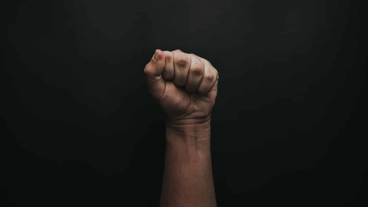 A powerful image of a raised fist against a dark background, symbolizing strength and unity.