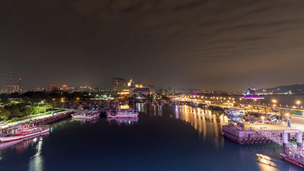 A vibrant night cityscape of a marina in Taipei, Taiwan, showcasing illuminated waterfront and urban skyline.