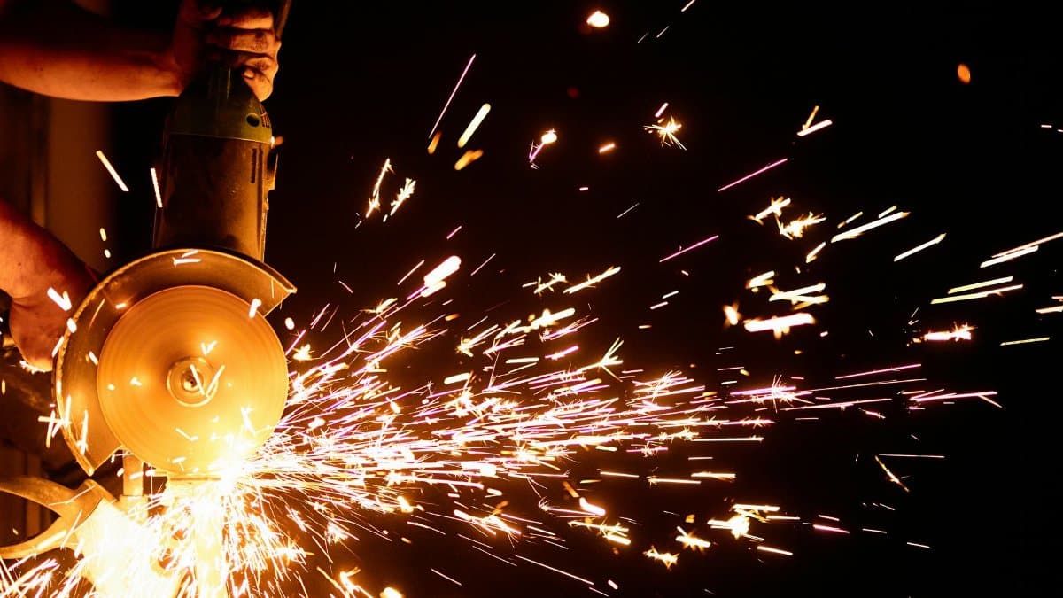 Close-up of angle grinder emitting bright sparks in a dark setting, showcasing industrial craftsmanship.
