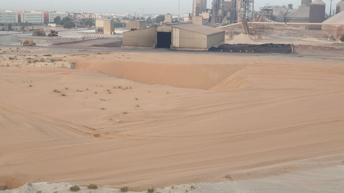 Desert landscape with industrial warehouse and factory structures.