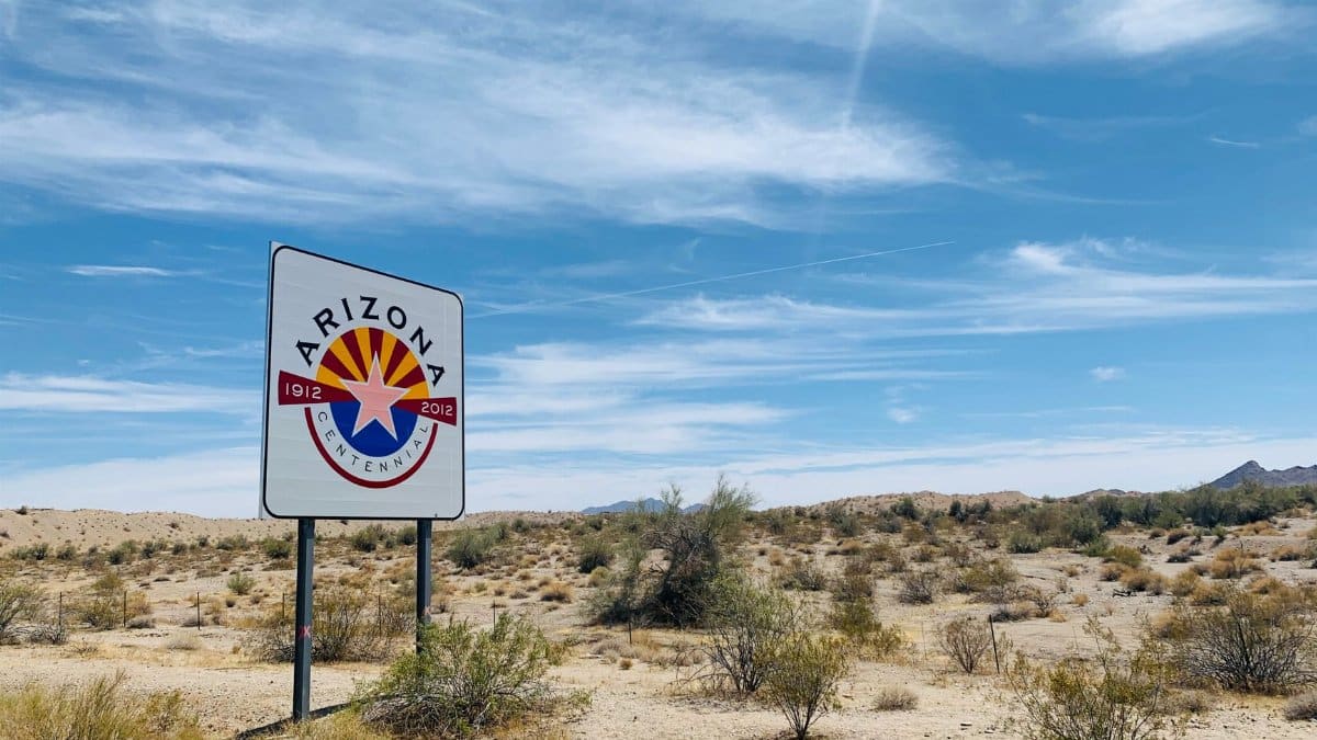 Desert landscape with Arizona Centennial sign and clear blue sky.