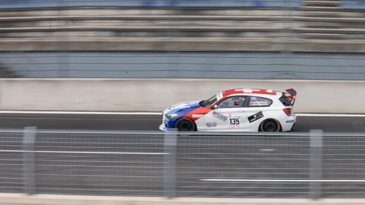 Speeding race car in motion blur on a German racetrack with a dynamic background.