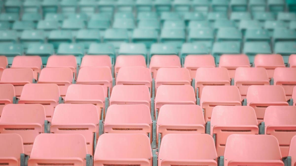Empty pastel pink and mint green stadium seats, artistically arranged in rows.