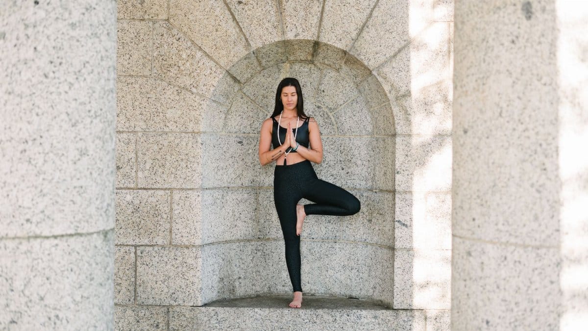 A woman practicing yoga in a peaceful, stone archway setting, embodying balance and mindfulness.