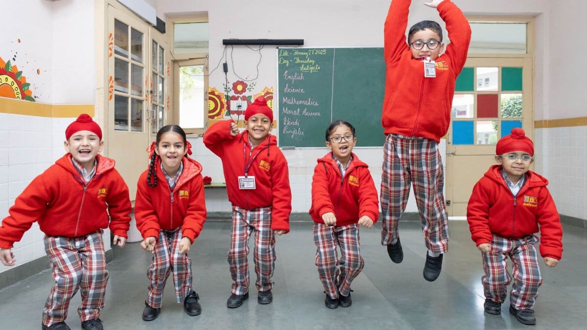 Group of cheerful school children jumping in a lively classroom setting, showcasing youthful energy.