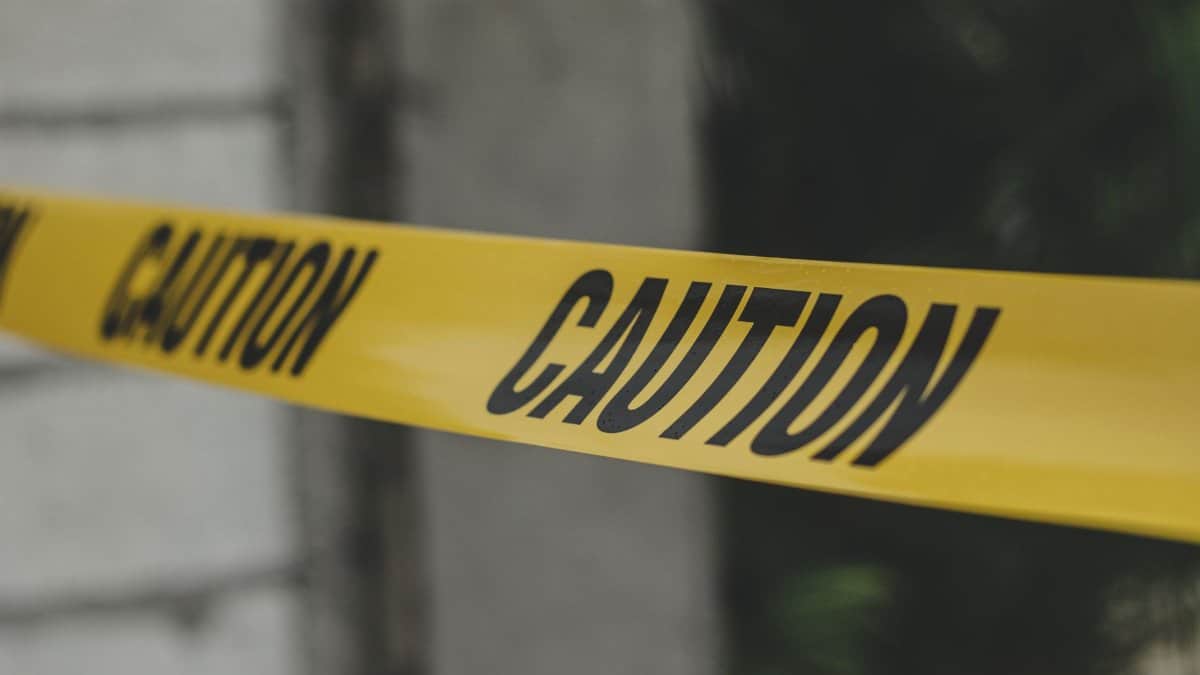 Close-up view of yellow caution tape creating a warning barrier outdoors.