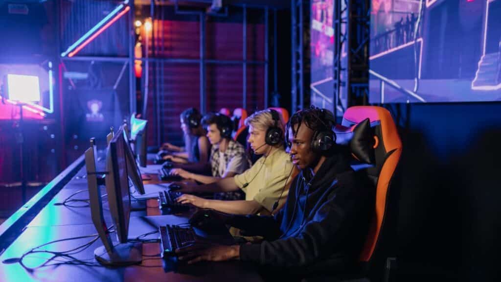 A group of focused teenagers playing in an esports tournament setup with gaming chairs and monitors.