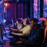 A group of focused teenagers playing in an esports tournament setup with gaming chairs and monitors.