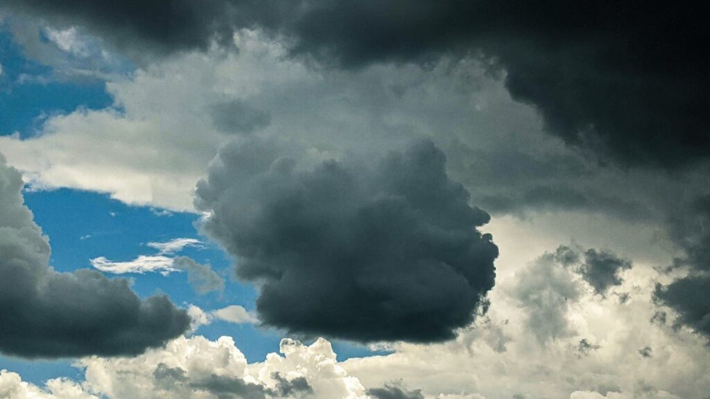 Cloudy sky with thick gray cumulus clouds floating high in air on blue sky in nature in overcast weather on summer day