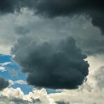 Cloudy sky with thick gray cumulus clouds floating high in air on blue sky in nature in overcast weather on summer day