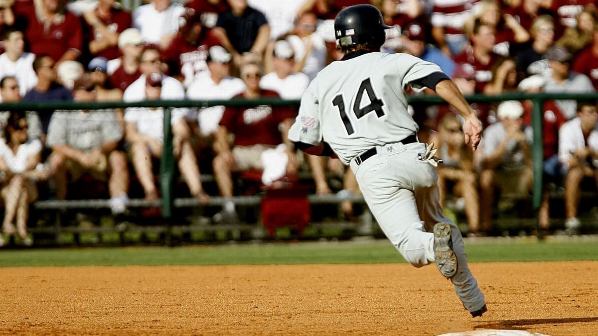 Baseball player in action running towards a base during a daytime game with spectators.
