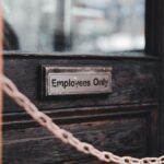 Close-up of an 'Employees Only' sign on a rustic wooden door secured by a chain.