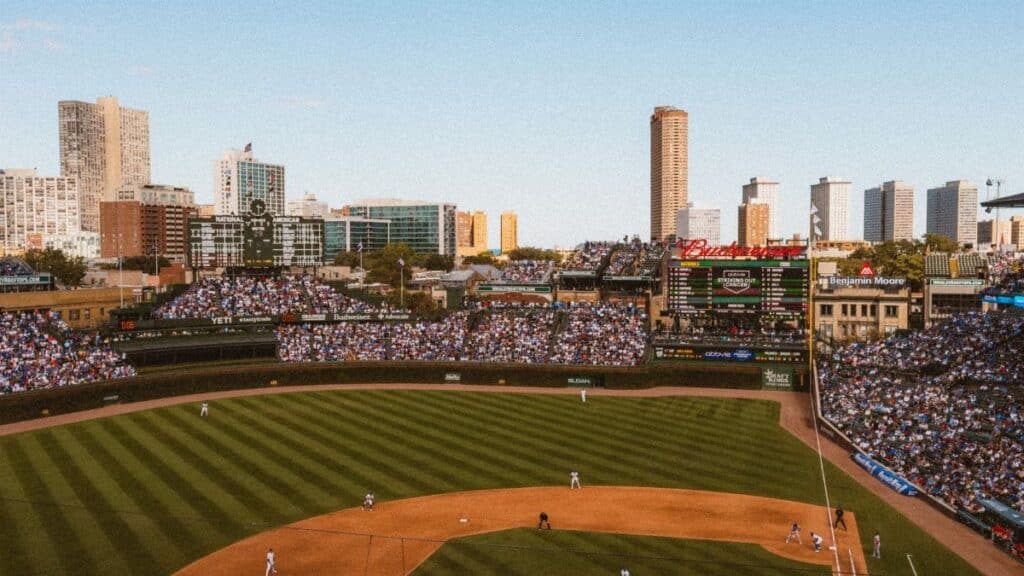 Aerial view of a lively baseball game at a famous stadium with city skyline.