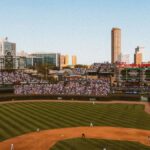 Aerial view of a lively baseball game at a famous stadium with city skyline.