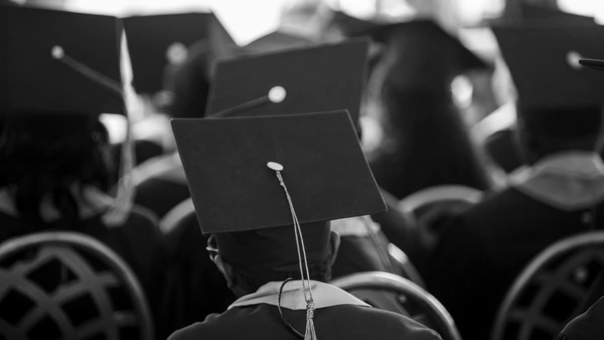 Black and white photograph of students wearing mortarboards at a graduation ceremony.