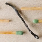 Charred match surrounded by green-tipped matches symbolizing burnout and contrast.