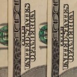 Detailed close-up of multiple US hundred dollar bills, showcasing currency design.