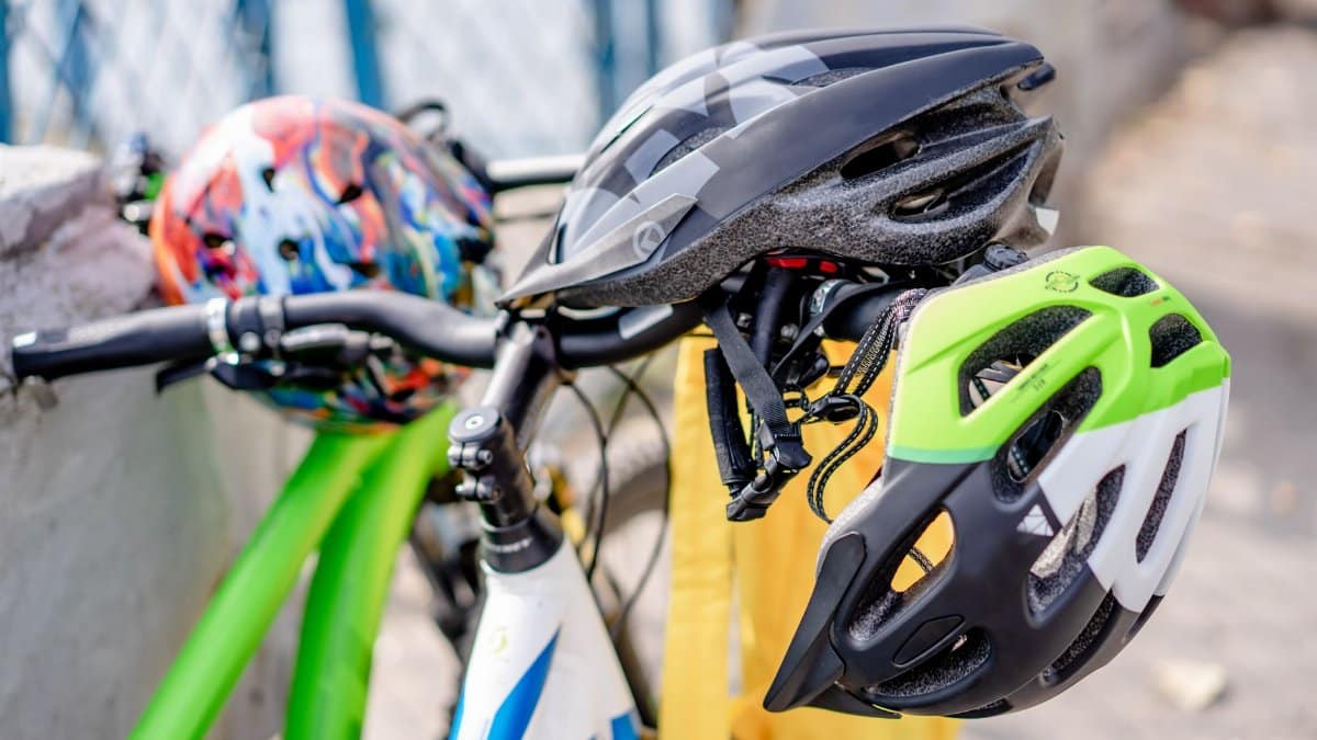 Close-up of brightly colored bicycle helmets resting on bike handlebars, emphasizing safety.
