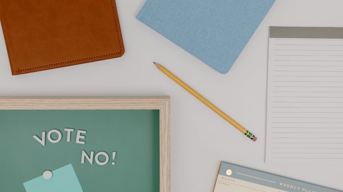 A top view flat lay of office supplies with a 'Vote No' message on a green board.