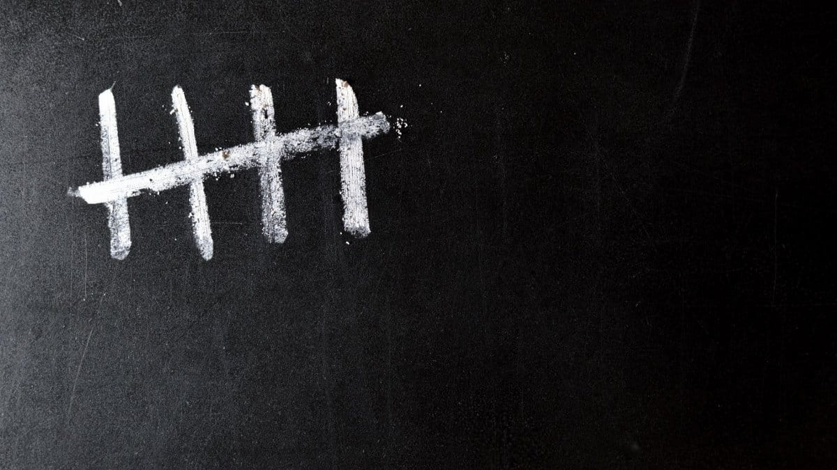 Five chalk tally marks on a black chalkboard background.