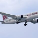 Qatar Airways Boeing 787 soaring against a clear sky, capturing aviation elegance.