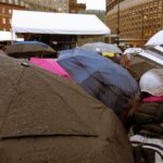 Crowd with umbrellas in a rainy Boston square, showcasing urban weather scene.
