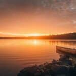 A tranquil sunset over a lake in Ely, Minnesota, featuring a canoe by the rocky shore.