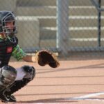 Young boy playing as a baseball catcher, crouched and ready during a daytime game.