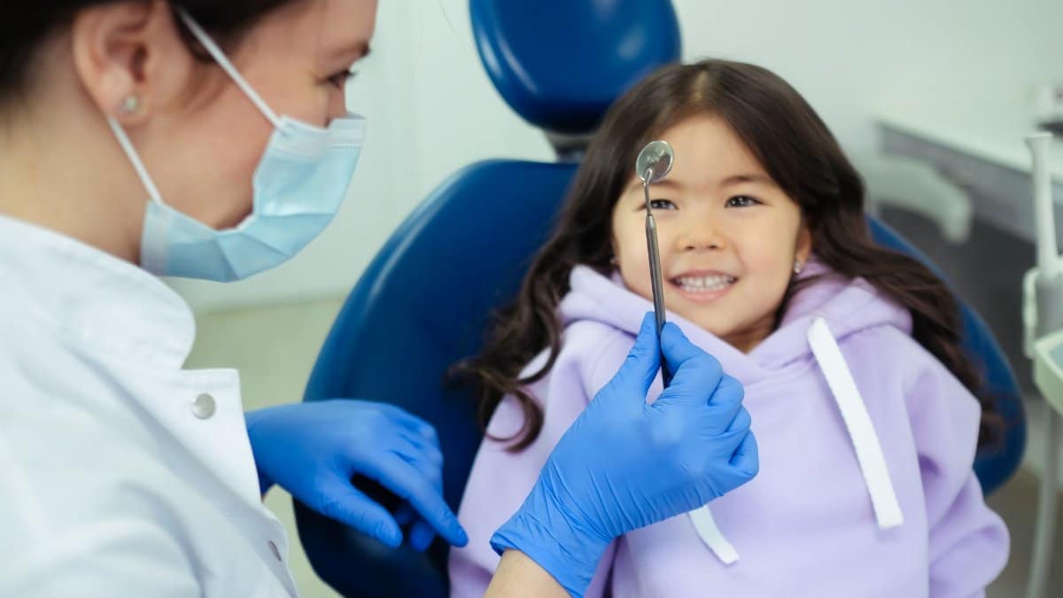 A dentist and a smiling child during a friendly dental check-up in a clinic.