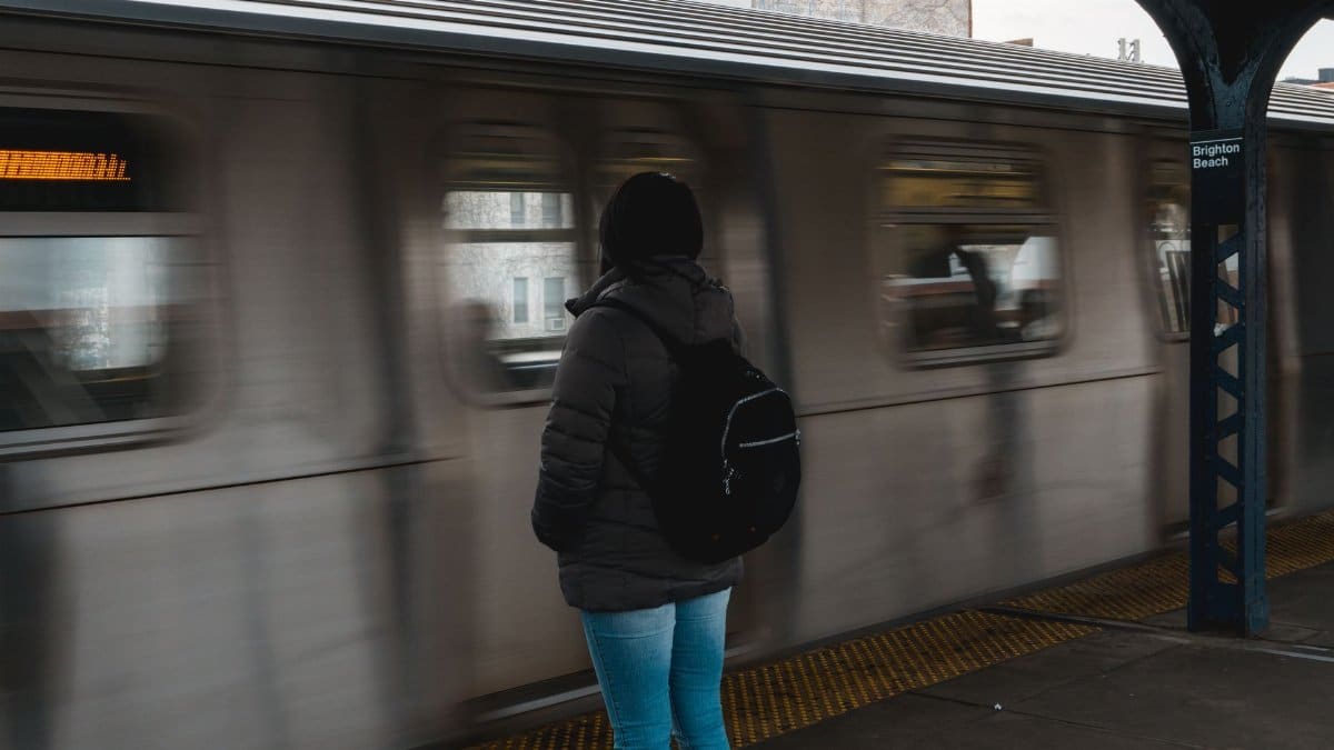 A person in winter clothing waiting for a train at Brighton Beach subway station.