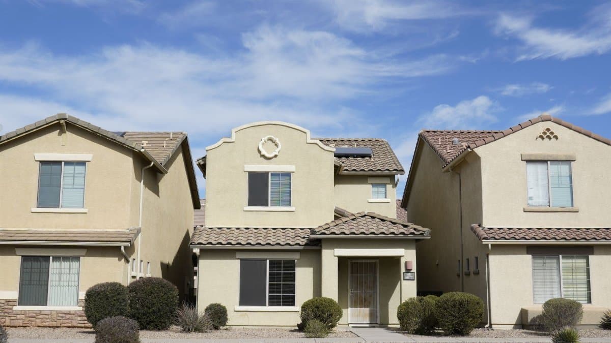 Three adjacent houses in a suburban neighborhood of Tucson, Arizona under a clear sky.