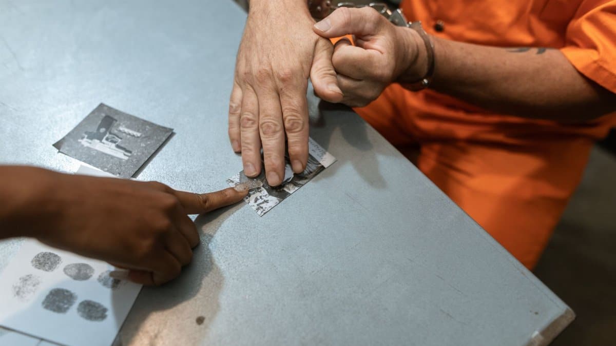 Close-up of fingerprinting during a criminal investigation with handcuffed individual.