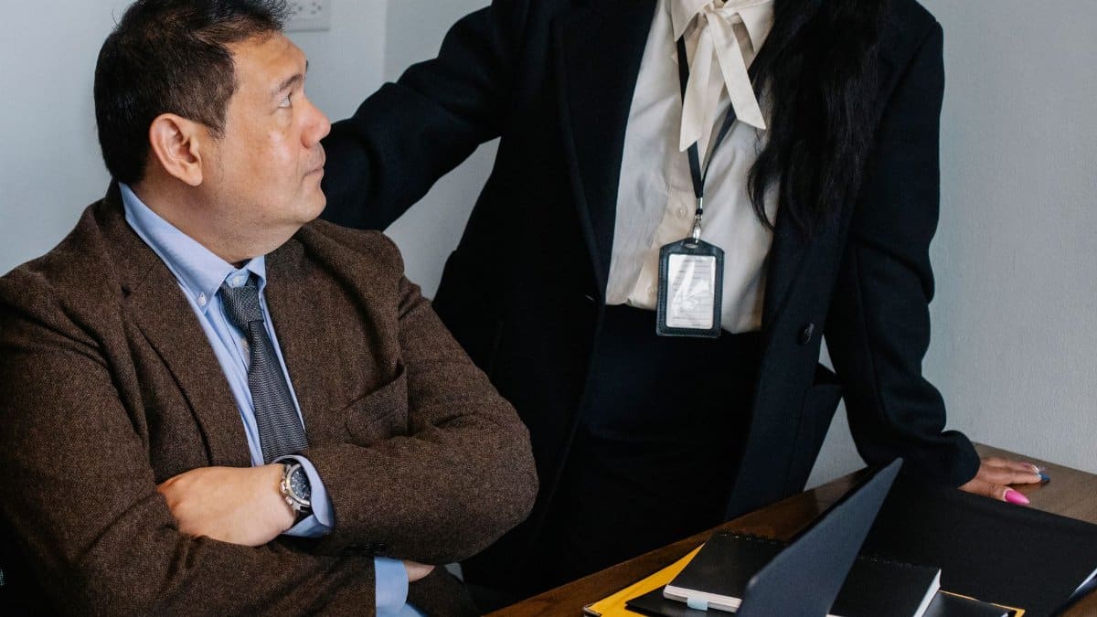 Serious colleagues wearing formal clothes gathering at table and having discussion while working together in contemporary office