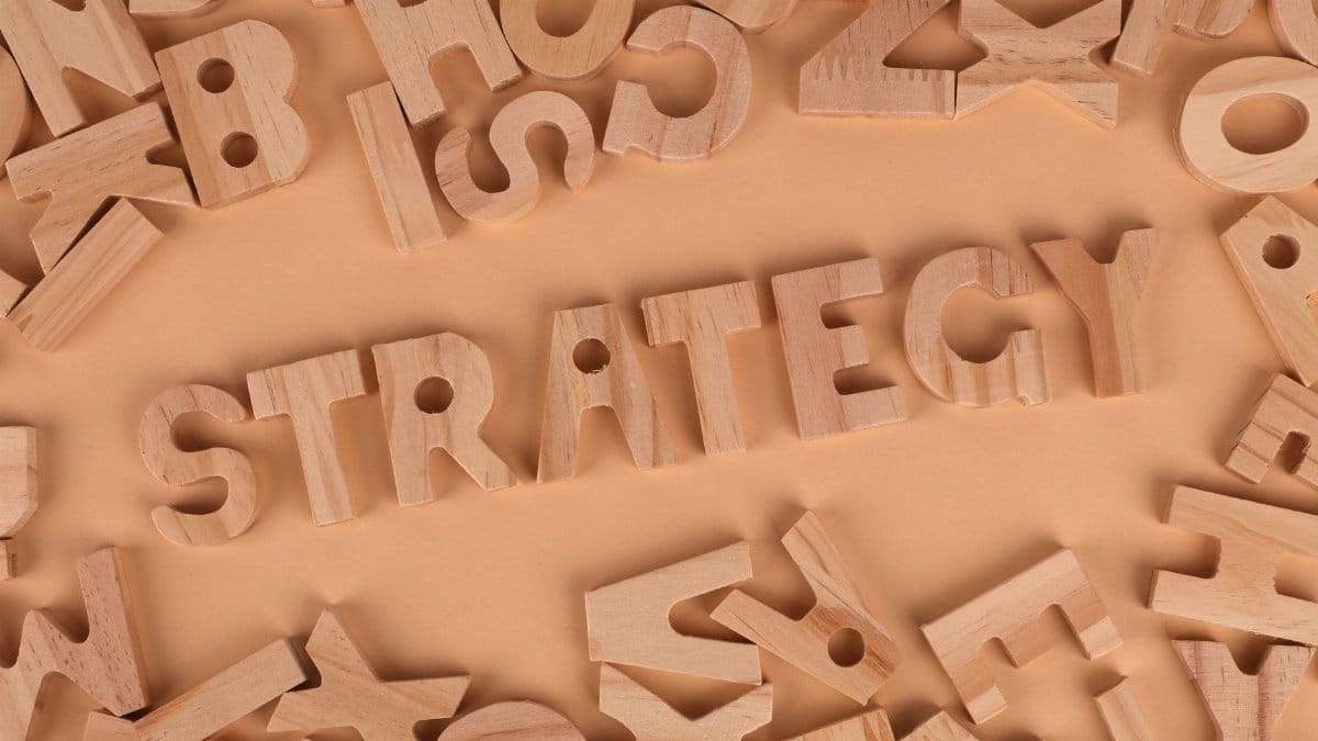 Overhead view of wooden letter blocks spelling 'Strategy' on a soft brown background.
