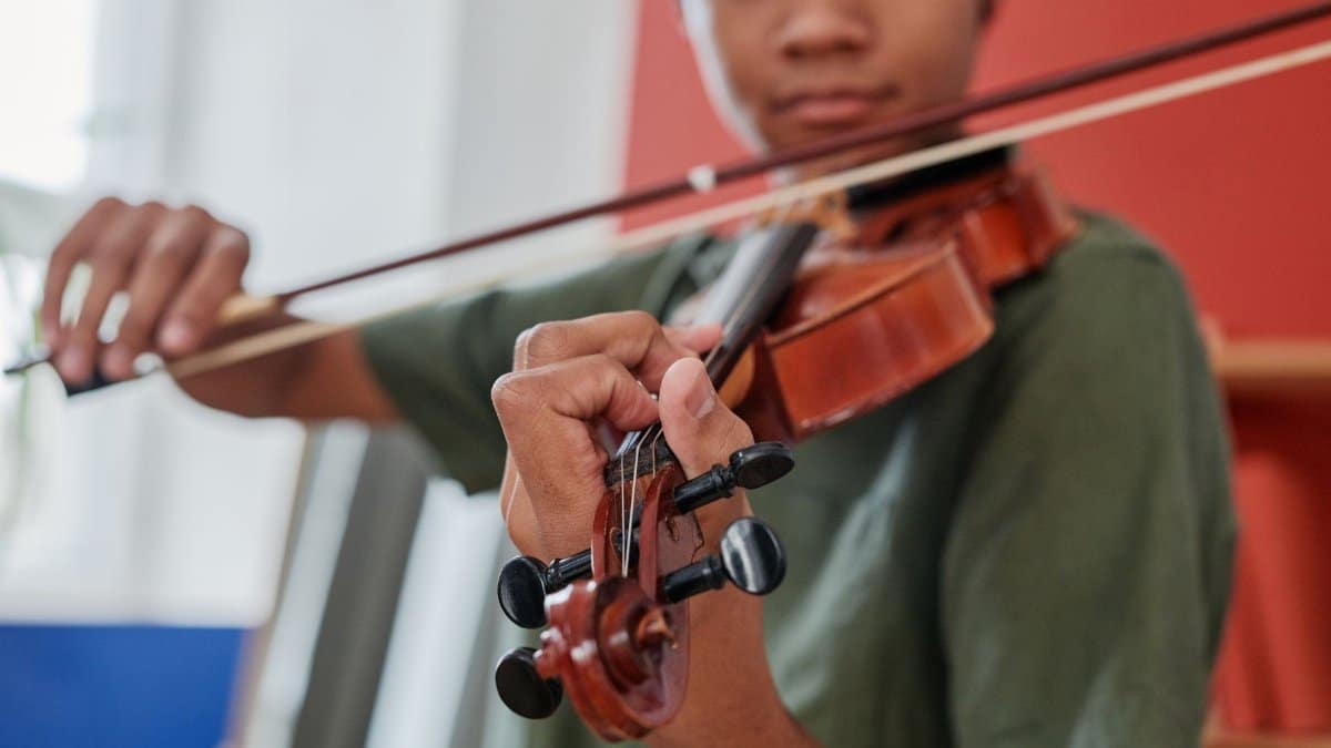 Close-up of an African American man skillfully playing a violin indoors.