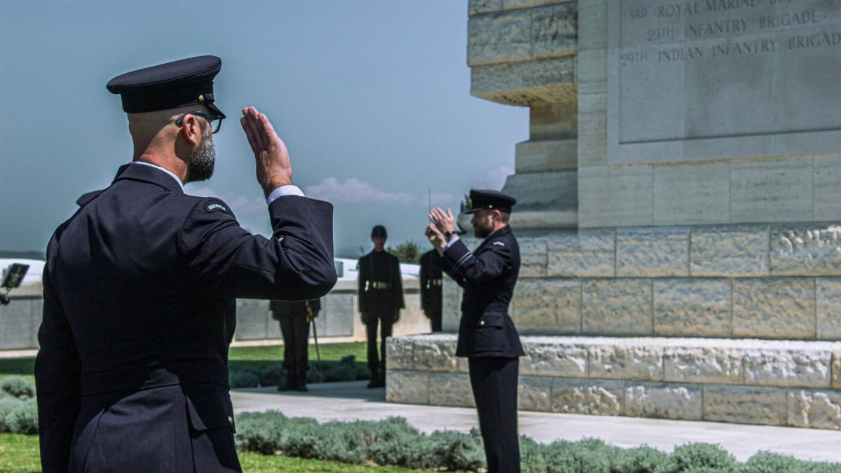 Uniformed guards salute during a military ceremony at a monument.