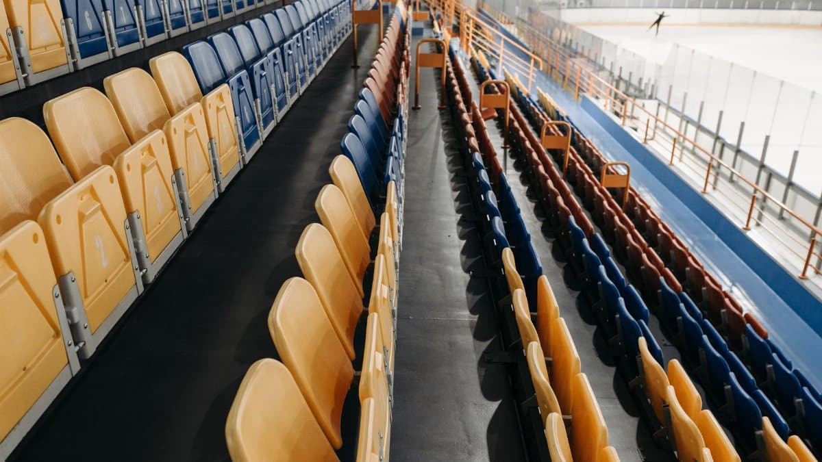 An indoor ice rink with empty stadium seating, perfect for events.