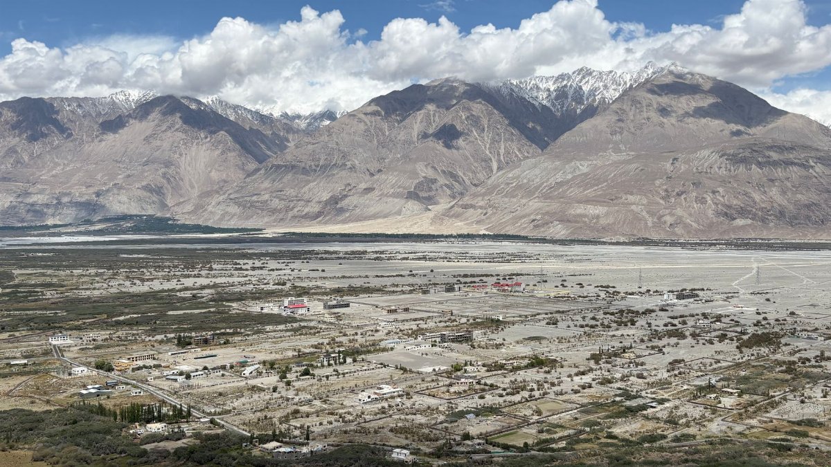 A stunning aerial view of Nubra Valley with mountains and scattered settlements beneath a blue sky.