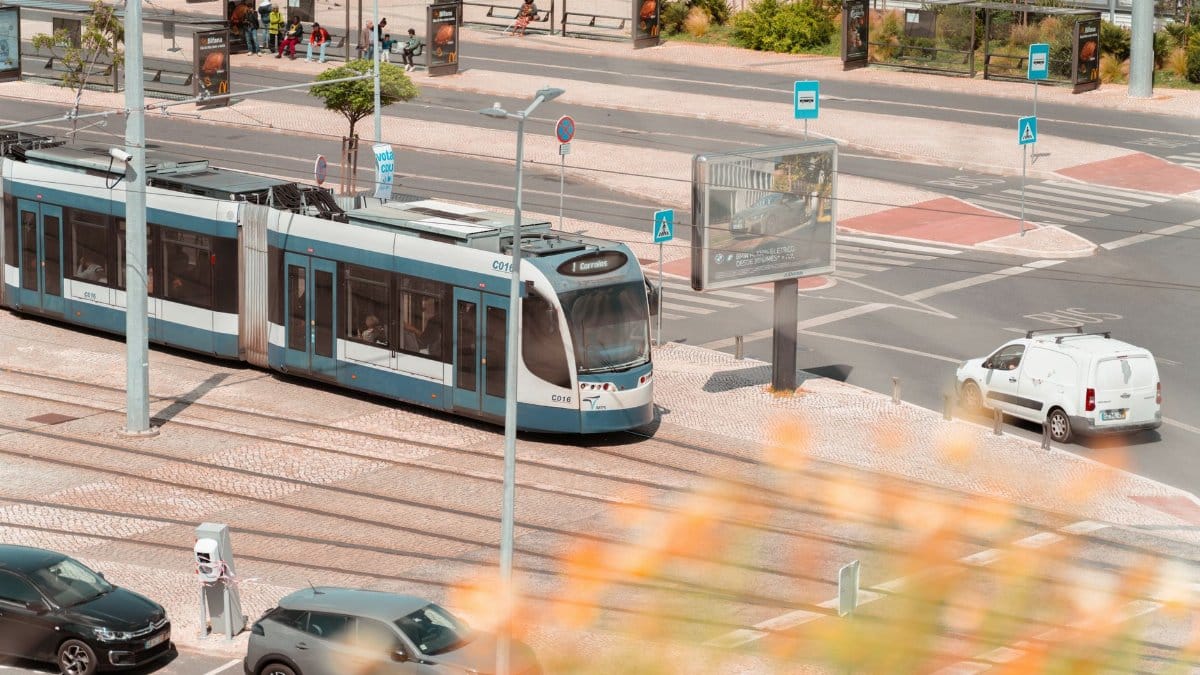 A contemporary tram navigates through Lisbon's city streets.
