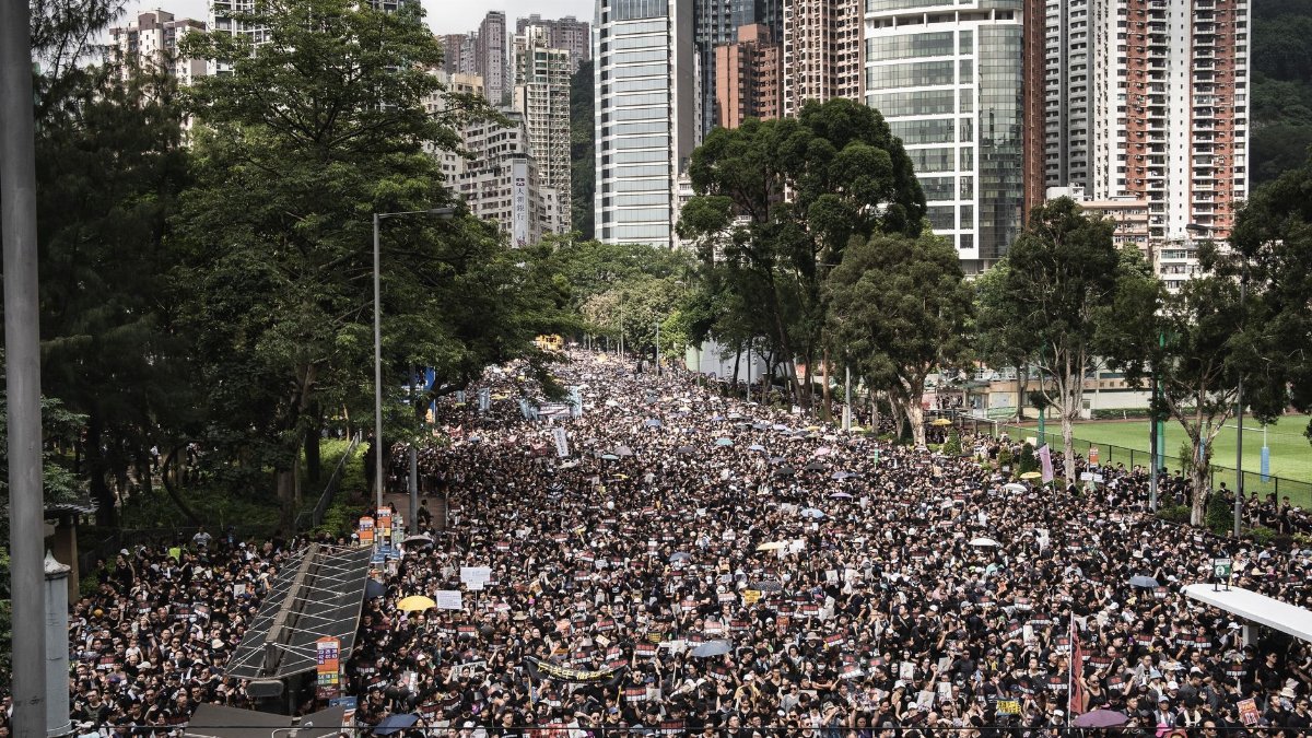 A large crowd protesting in the streets of Hong Kong amidst skyscrapers.
