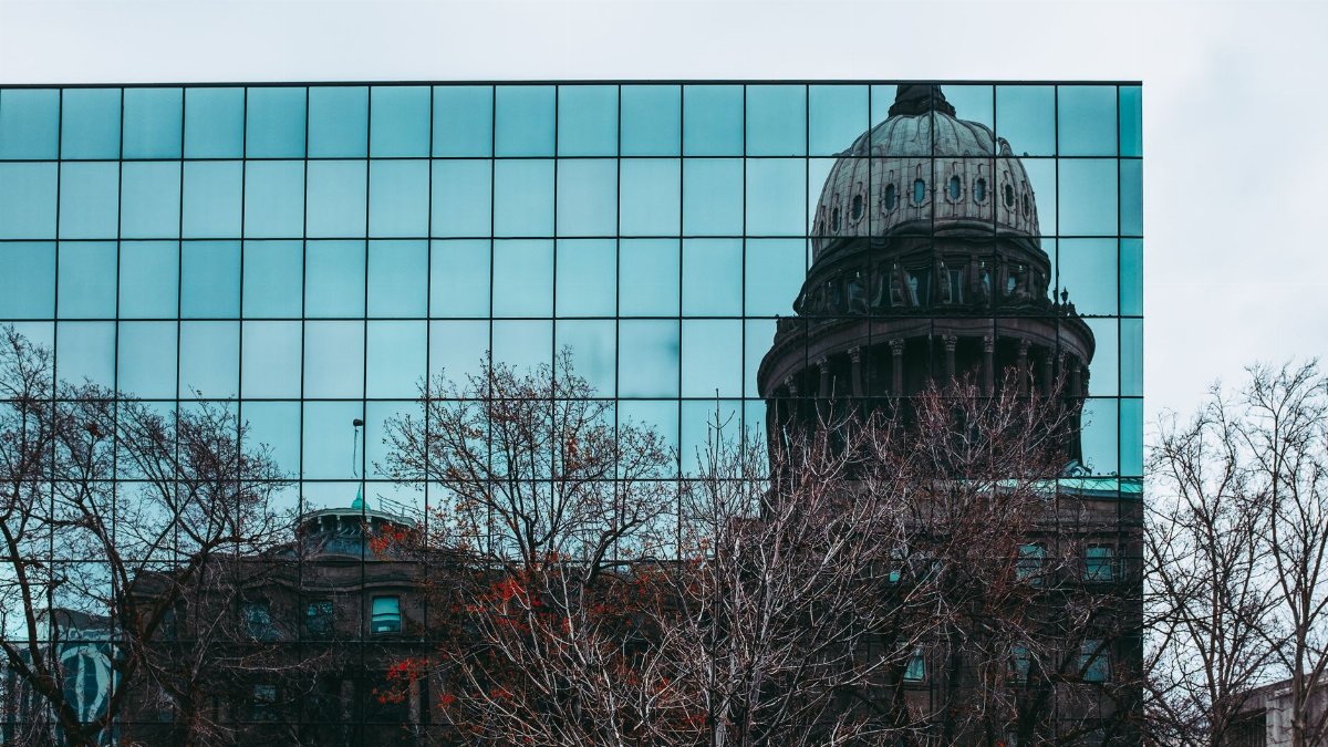 Reflection of Idaho State Capitol in a mirrored building facade in Boise, ID.