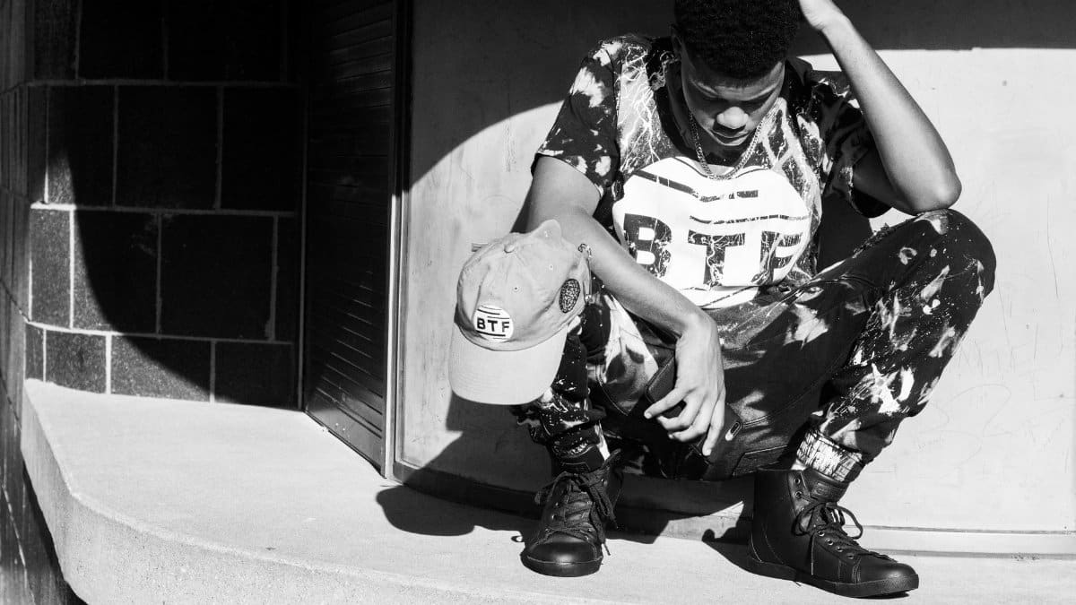 Black and white portrait of a man in stylish urban wear squatting in Washington, DC.
