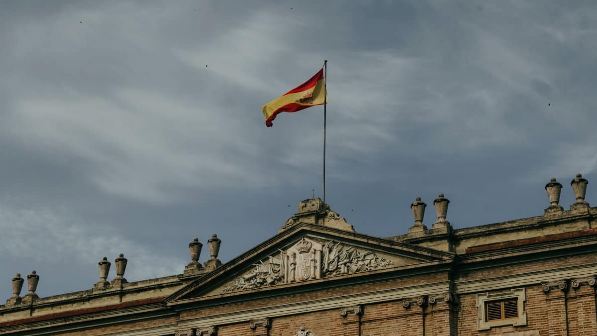Spanish flag flying over a historic building in Valencia, Spain under a cloudy sky.