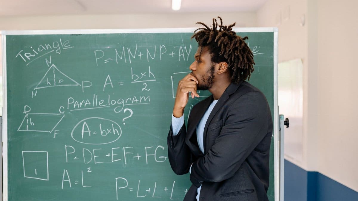 Teacher contemplating in front of a chalkboard with math equations.